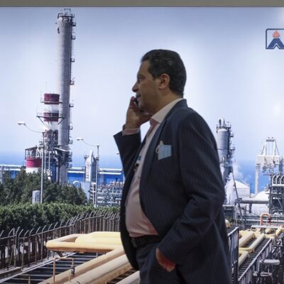Two years after the COVID-19 outbreak in Iran, An Iranian visitor speaks on his cellphone while walking past an image of gas facilities at the 26th International Oil, Gas, Refining and Petrochemical Exhibition in Tehran on May 13, 2022. (Photo by Morteza Nikoubazl/NurPhoto)NO USE FRANCE