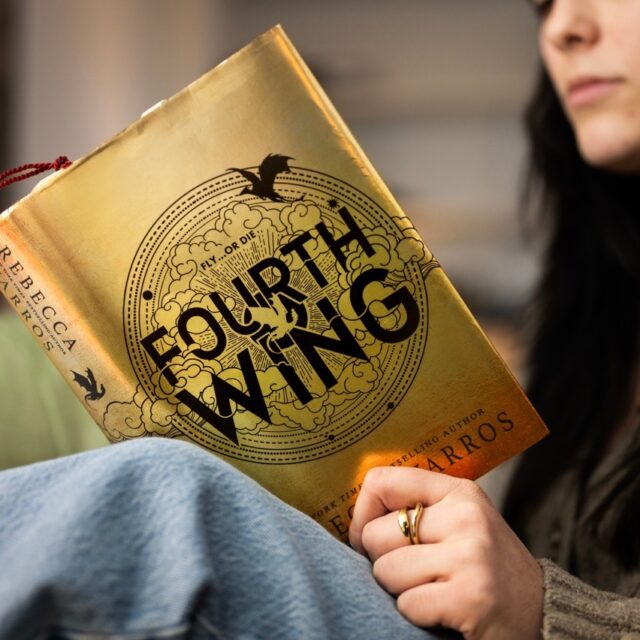 A member of the Northeastern community reads Fourth Wing, the first book in the best-selling romantasy series by Rebecca Yarros.