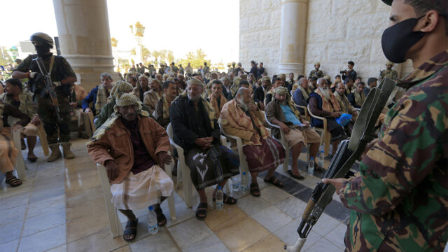 Huthi fighters stand guard around newly-released Yemeni prisoners wait to be united with their relatives, in Sanaa on January 25, 2025. (Photo by Mohammed HUWAIS / AFP) (Photo by MOHAMMED HUWAIS/AFP via Getty Images)