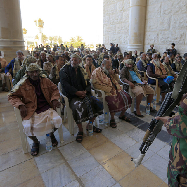Huthi fighters stand guard around newly-released Yemeni prisoners wait to be united with their relatives, in Sanaa on January 25, 2025. (Photo by Mohammed HUWAIS / AFP) (Photo by MOHAMMED HUWAIS/AFP via Getty Images)
