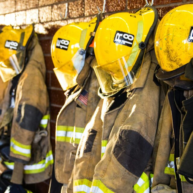 Firefighter uniforms are hung up in a row.