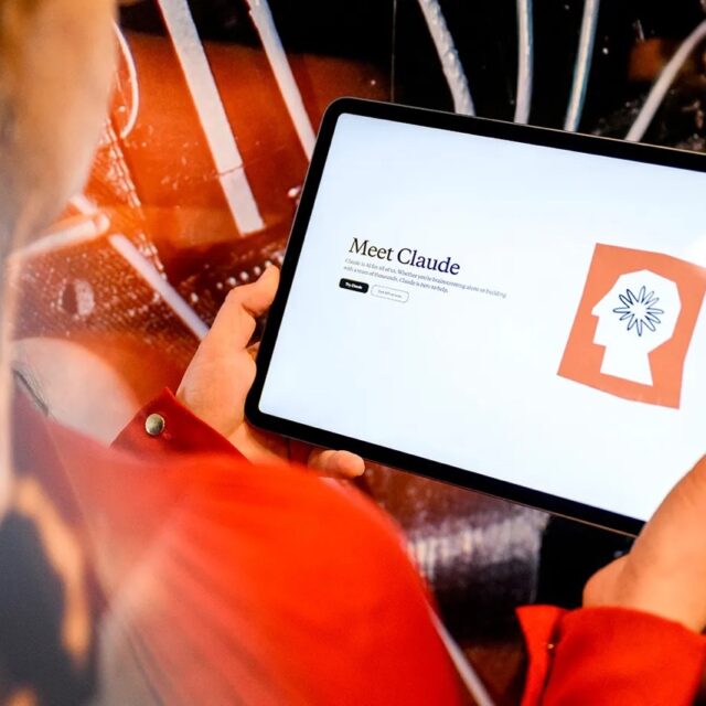 Student holds tablet with Claude AI.