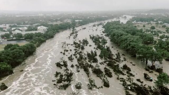 Major flood sweeping away trees with houses nearby.