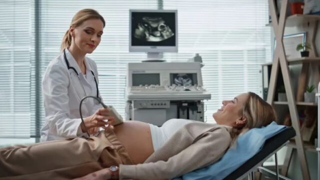 A doctor examining a pregnant patient with an ultrasound machine in a clinic.