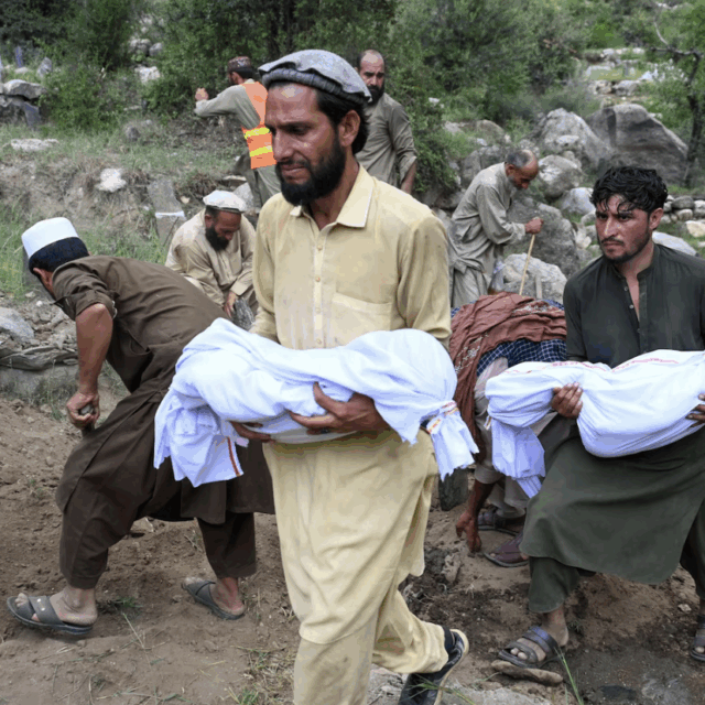 People carry the bodies of earthquake victims for their funerals on Monday