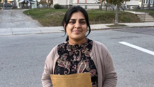 Sadia Mansoor, a volunteer with the nonprofit Worcester Interfaith, holds a folder containing information about the upcoming election as she goes door-knocking in the Main South neighborhood on Oct. 3, 2025.