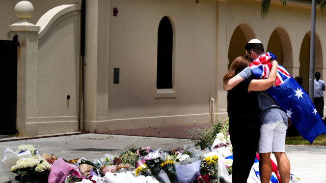 A couple lay flowers at a tribute to shooting victims outside the Bondi Pavilion at Sydney's Bondi Beach, Monday, Dec. 15, 2025, a day after a shooting. (AP Photo/Mark Baker)