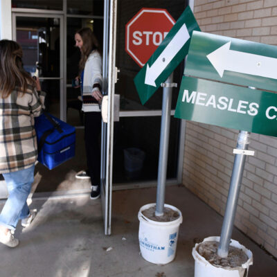 FILE - Health department staff members enter the Andrews County Health Department measles clinic carrying doses of the measles, mumps and rubella vaccine, Tuesday, April 8, 2025, in Andrews, Texas. (AP Photo/Annie Rice, File)