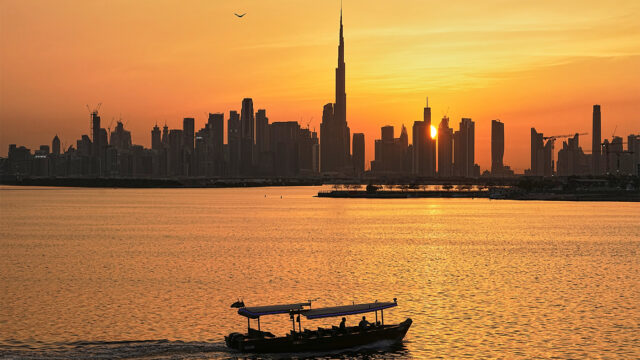 A man steers a boat during sunset, as the city skyline with Burj Khalifa is seen in the background at Dubai Creek Harbour in Dubai, United Arab Emirates, Wednesday, March 11, 2026. (AP Photo/Fatima Shbair)