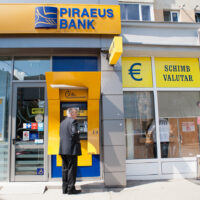 TIMISOARA, ROMANIA - APRIL 14: A man withdraw some cash from the Piraeus Bank on April 14, 2013 in Timisoara, Romania. Romania has abandoned a target deadline of 2015 to switch to the single European currency and will now submit to the European Commission a programme on progress towards the adoption of the Euro, which for the first time will not have a target date. (Photo by Marco Secchi/Getty Images)