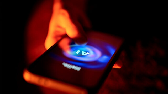 A hand interacts with an AI chatbot on a smartphone screen, glowing under dramatic red and blue lighting in a dark environment.