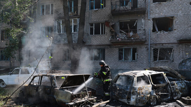 Rescue workers try to put out a fire of a residential building and cars burning after a Russian air guided bomb strike in Zaporizhzhia, Ukraine, Monday, Aug. 10, 2026. (AP Photo/Kateryna Klochko)