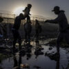 The U.S. is seen in the background as Joiner, a 22-year-old migrant from Venezuela, hands his three-year-old daughter Ivanna to a fellow compatriot as they navigate the riverbed of the Rio Grande while searching for an entry point into the U.S. from along the international boundary between Ciudad Juarez, Mexico, and El Paso, Texas, at sunrise on April 20, 2024. REUTERS/Adrees Latif SEARCH 